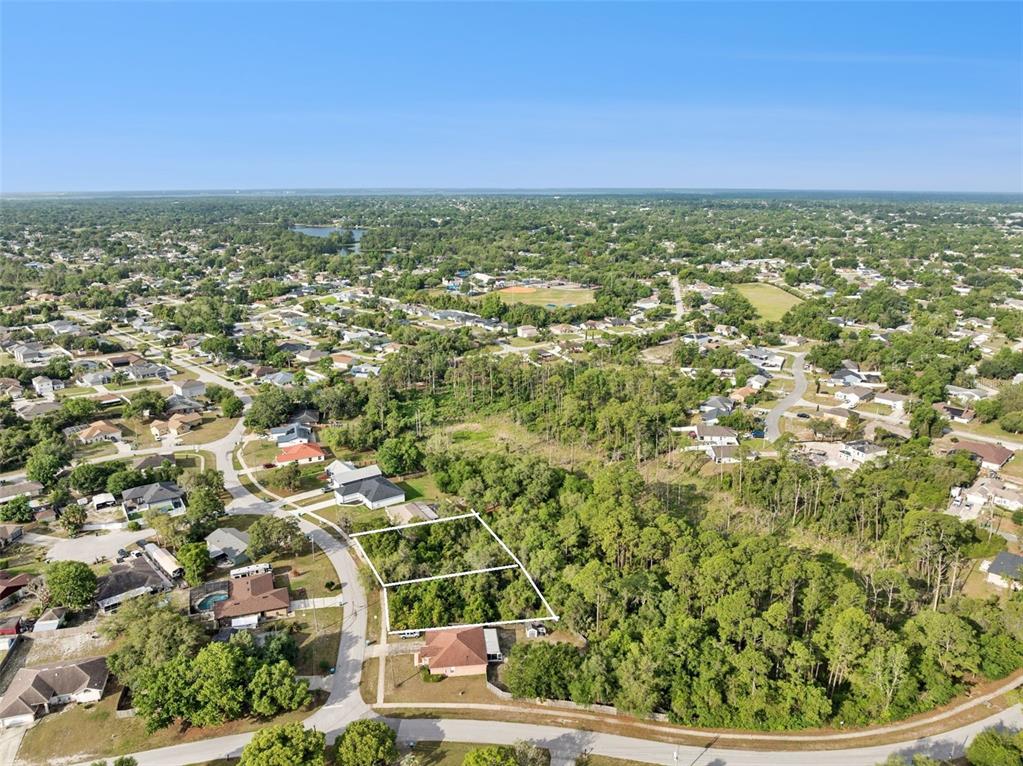 An aerial view shows two adjacent vacant residential lots outlined in white within a neighborhood — 1680  & 1672 GREGORY DRIVE, DELTONA, FL