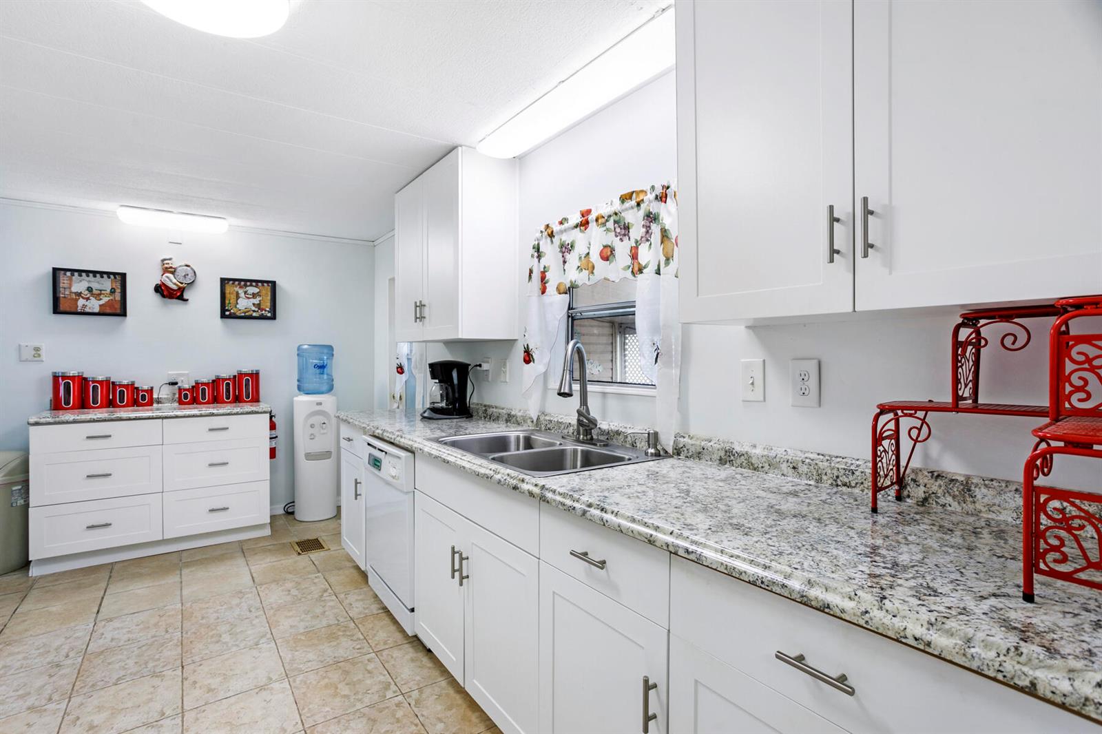 A kitchen features white cabinets, granite countertops, a double sink, and light-colored tile flooring — 37026 Exuma Bay, Boynton Beach FL 33436, BOYNTON BEACH, FL