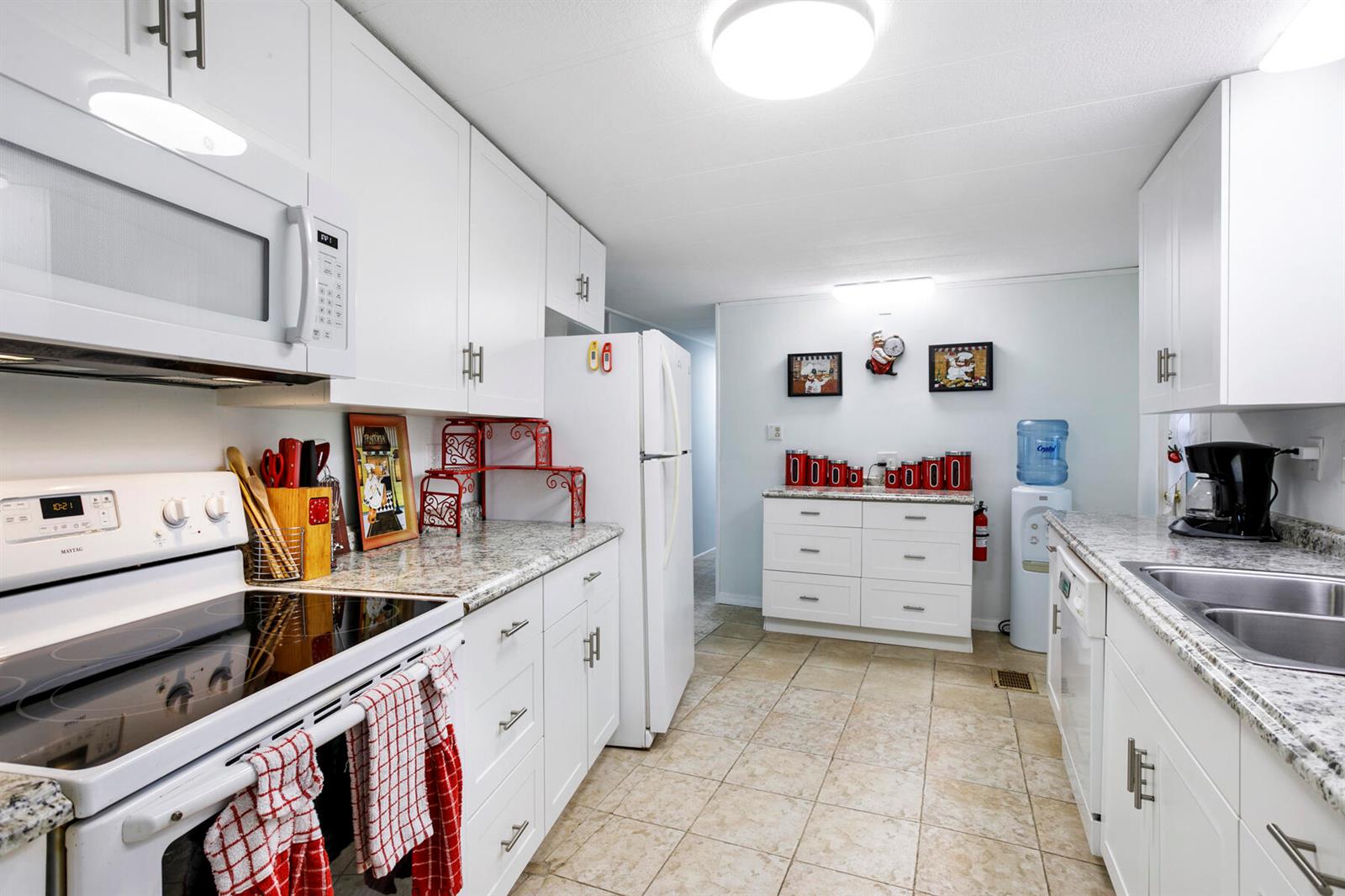 A bright kitchen features white cabinets, granite countertops, a white stove, and tile flooring — 37026 Exuma Bay, Boynton Beach FL 33436, BOYNTON BEACH, FL
