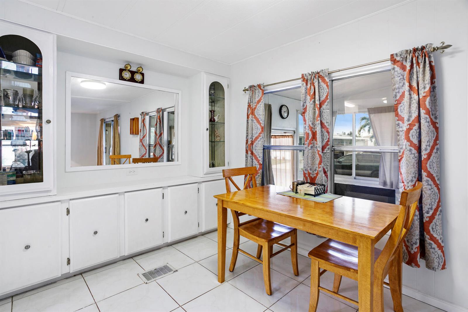A dining area features white cabinets, a large mirror, tile floors, and a wooden table — 37026 Exuma Bay, Boynton Beach FL 33436, BOYNTON BEACH, FL