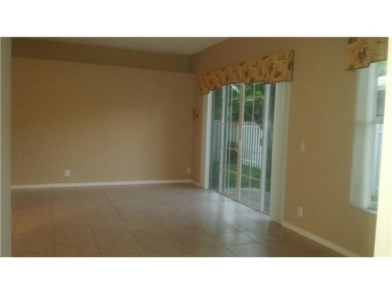 An empty room with beige walls, tile flooring, and a sliding glass door to a patio — 3529 Dunes Vista Drive, Pompano Beach FL 33069, POMPANO BEACH, FL