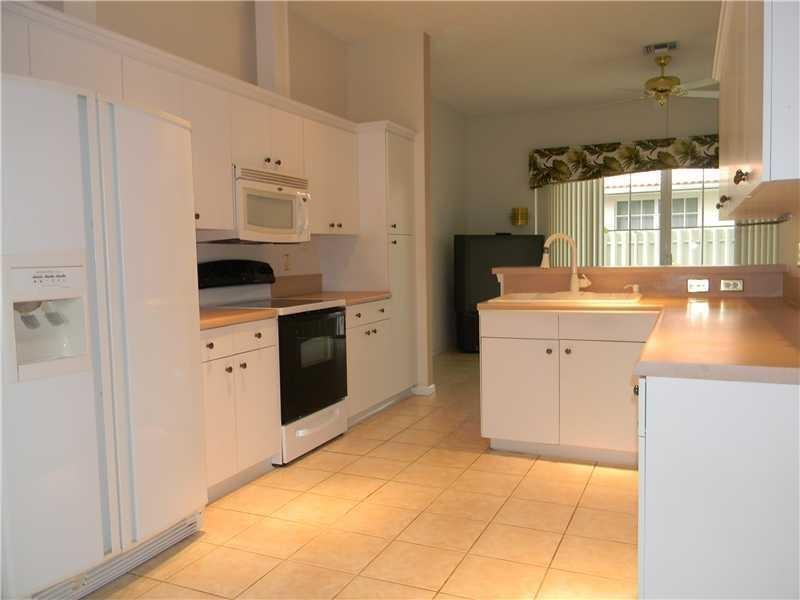 A kitchen with white cabinets, light countertops, tile flooring, and a white refrigerator — 3529 Dunes Vista Drive, Pompano Beach FL 33069, POMPANO BEACH, FL