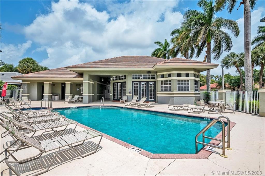 A swimming pool with lounge chairs sits in front of a one-story clubhouse building — 3529 Dunes Vista Drive, Pompano Beach FL 33069, POMPANO BEACH, FL