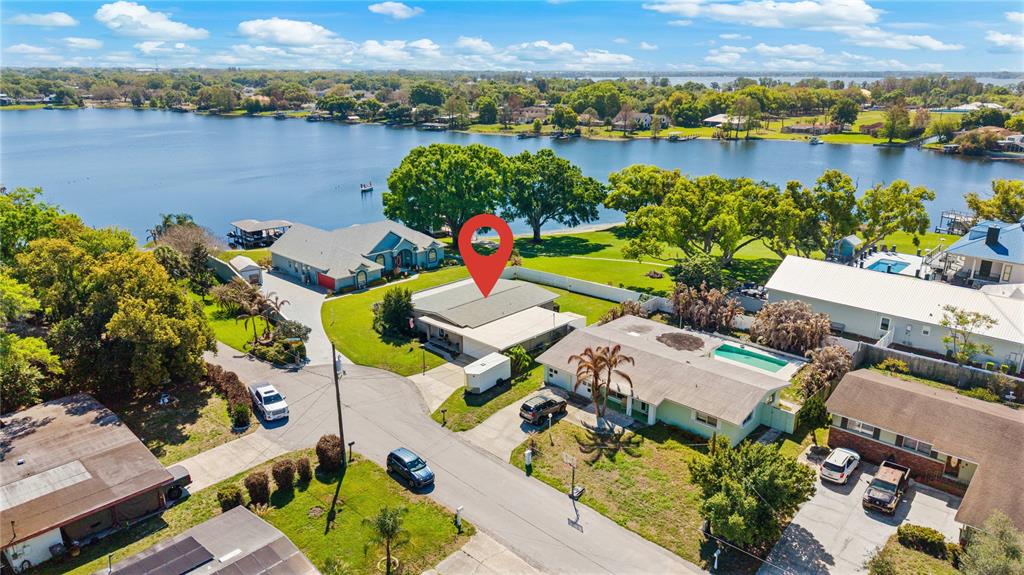 An aerial view shows a residential neighborhood with several houses situated along a large lake — 936 AVENUE T SE, WINTER HAVEN, FL