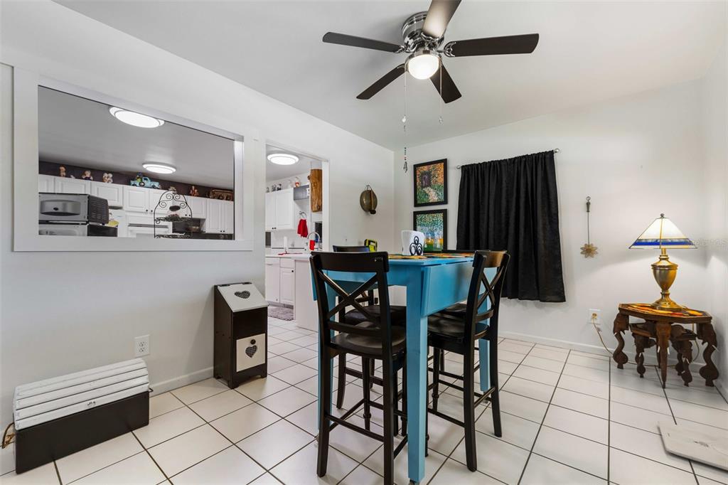 A dining area features a blue table, black chairs, white tile floors, and a pass-through window — 936 AVENUE T SE, WINTER HAVEN, FL