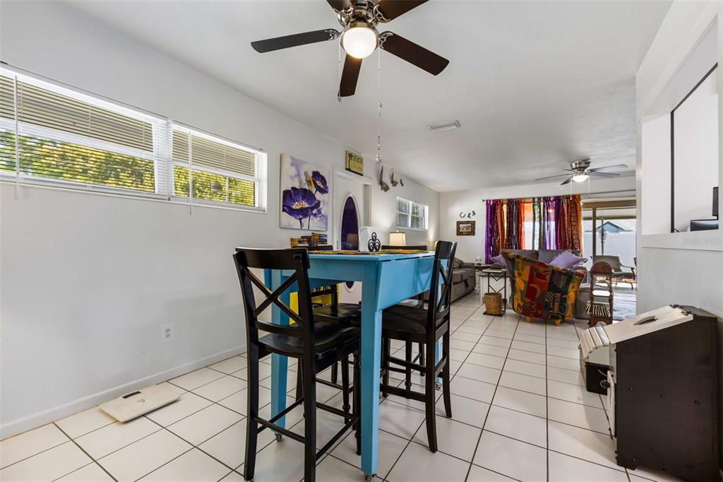 A dining area with a blue table and black chairs sits on white tiled floors — 936 AVENUE T SE, WINTER HAVEN, FL
