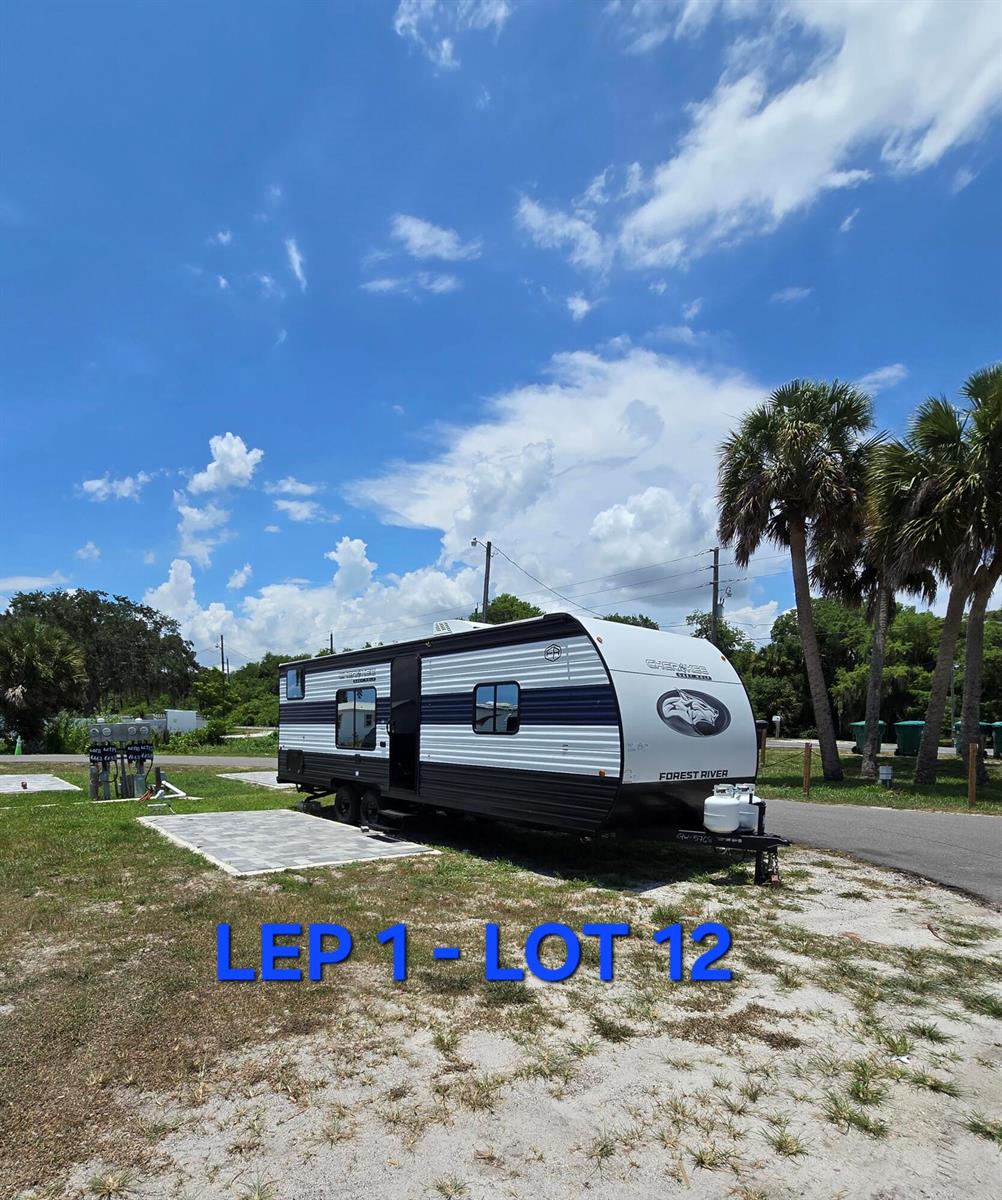 A Forest River Cherokee travel trailer is parked on a gravel lot with a paver pad — 6640 Us Hwy Se 441 SE, Okeechobee FL 34974, OKEECHOBEE, FL
