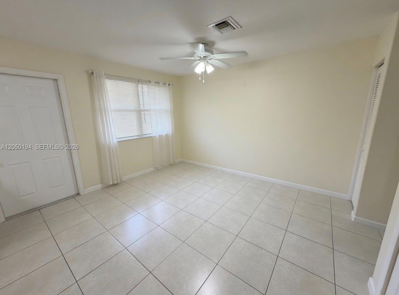 An empty room features light-colored tile flooring, a ceiling fan, and a window with blinds — 2227 Monroe St # 6, Hollywood FL 33020, HOLLYWOOD, FL