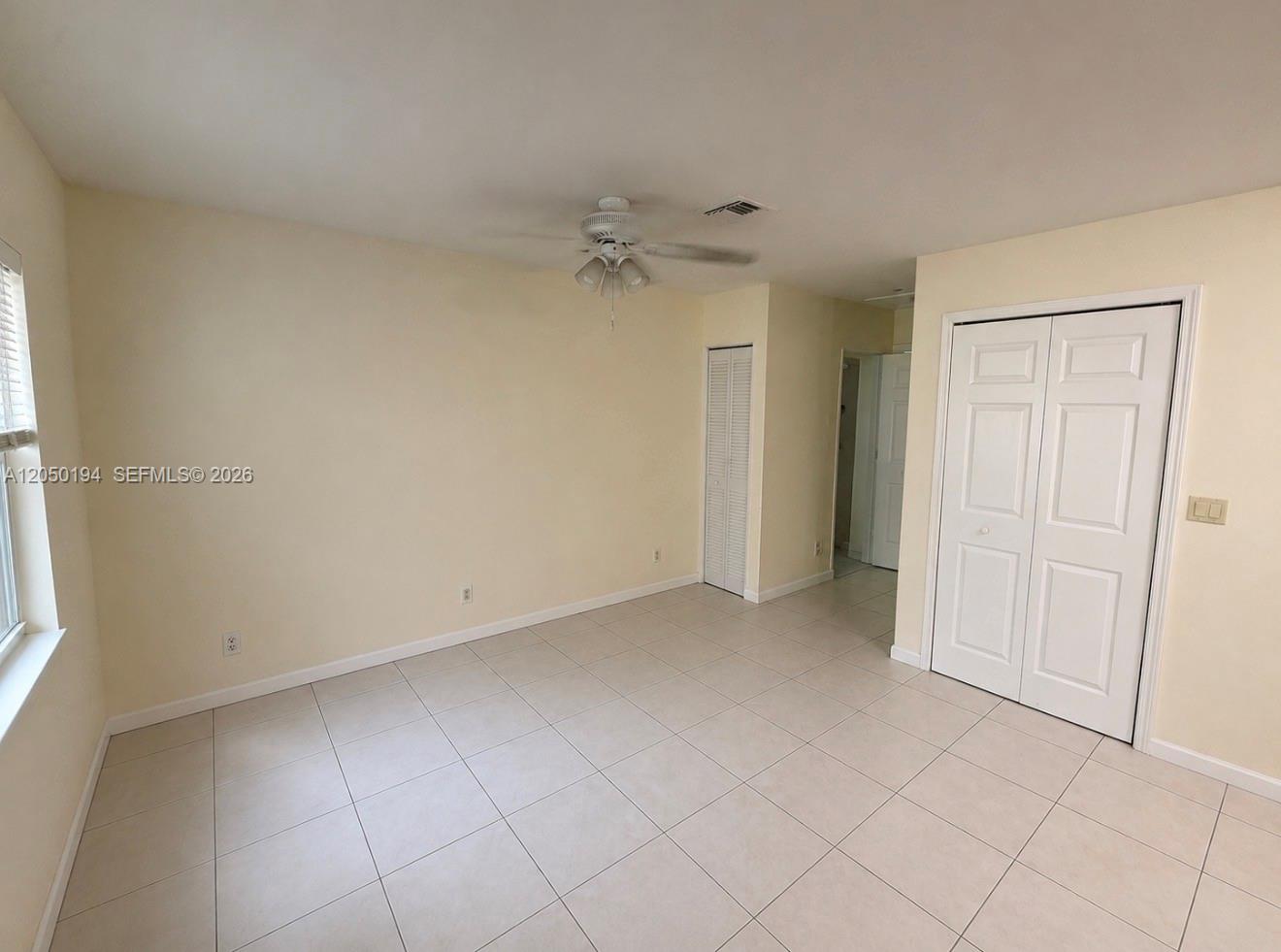 An empty bedroom features light-colored tile flooring, a ceiling fan, and white closet doors — 2227 Monroe St # 6, Hollywood FL 33020, HOLLYWOOD, FL