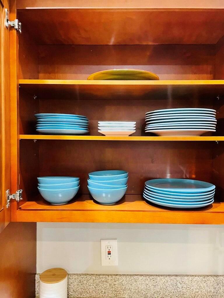 An open wooden cabinet displays stacks of blue plates and bowls on two shelves — 1317 Periwinkle Place, Wellington FL 33414, WELLINGTON, FL