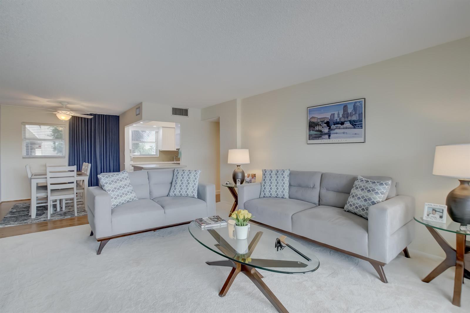 A living room with two gray sofas, a glass coffee table, and an adjacent dining area — 801 S Federal Highway # 308, Pompano Beach FL 33062, POMPANO BEACH, FL