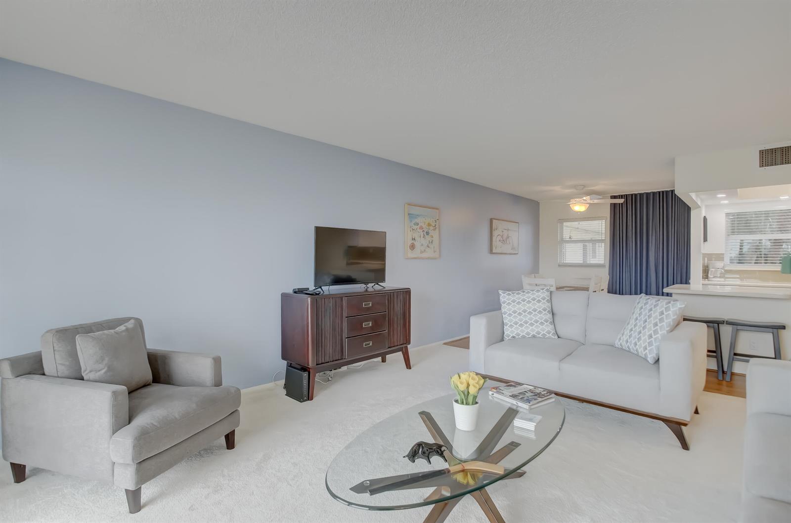 A living room features light blue walls, a grey sofa, an armchair, and a glass table — 801 S Federal Highway # 308, Pompano Beach FL 33062, POMPANO BEACH, FL