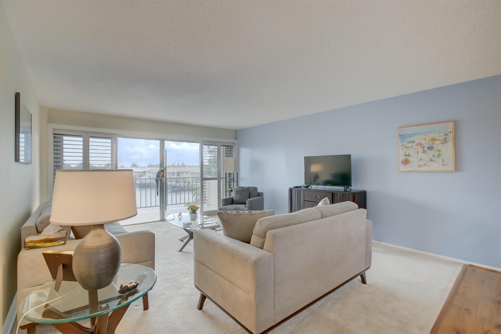 A living room features light blue walls, two beige sofas, and a sliding glass door — 801 S Federal Highway # 308, Pompano Beach FL 33062, POMPANO BEACH, FL
