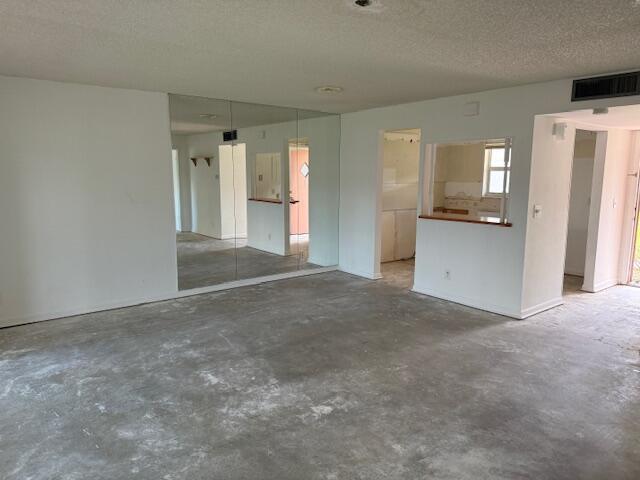 An empty room with concrete floors, a mirrored wall, and a kitchen pass-through window — 300 Bonnie Boulevard # 145, Palm Springs FL 33461, PALM SPRINGS, FL
