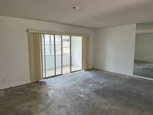 An empty room with concrete floors, white walls, sliding glass doors, and a mirrored wall — 300 Bonnie Boulevard # 145, Palm Springs FL 33461, PALM SPRINGS, FL