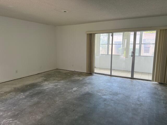 An empty room with white walls, a concrete floor, and sliding glass doors to a patio — 300 Bonnie Boulevard # 145, Palm Springs FL 33461, PALM SPRINGS, FL