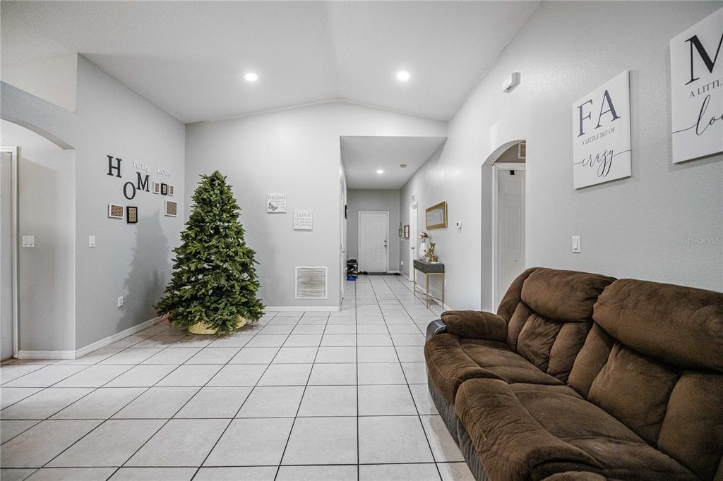 A spacious living area features light tile flooring, a vaulted ceiling, and a Christmas tree — 141 FLATFISH COURT, KISSIMMEE, FL