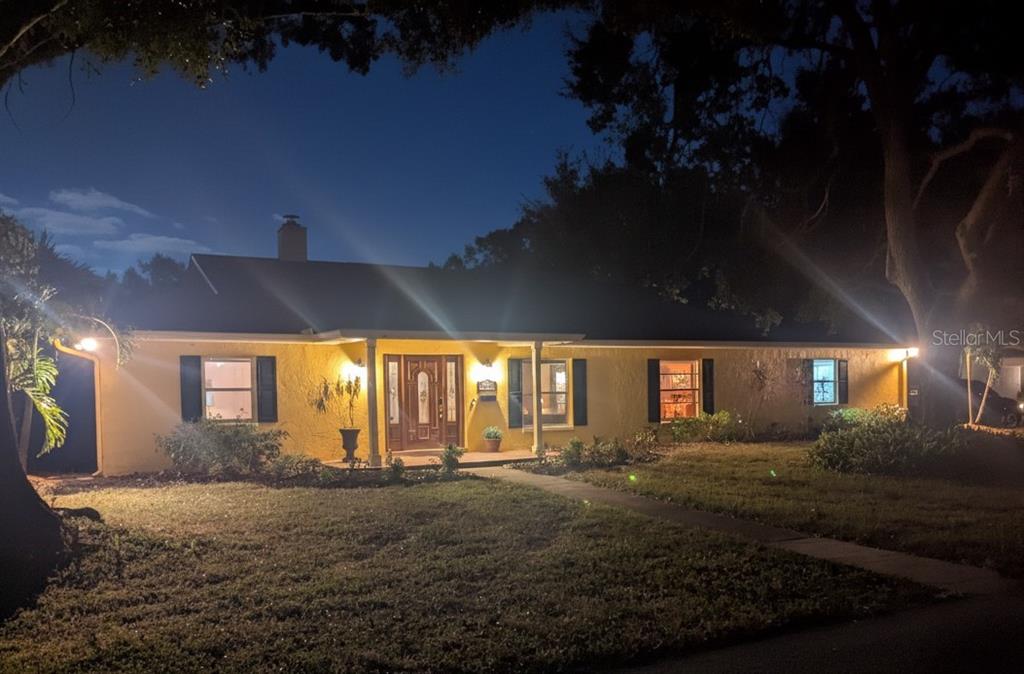 A single-story yellow house with dark shutters and a front porch at night — 5710 S BERNIE STREET, TAMPA, FL