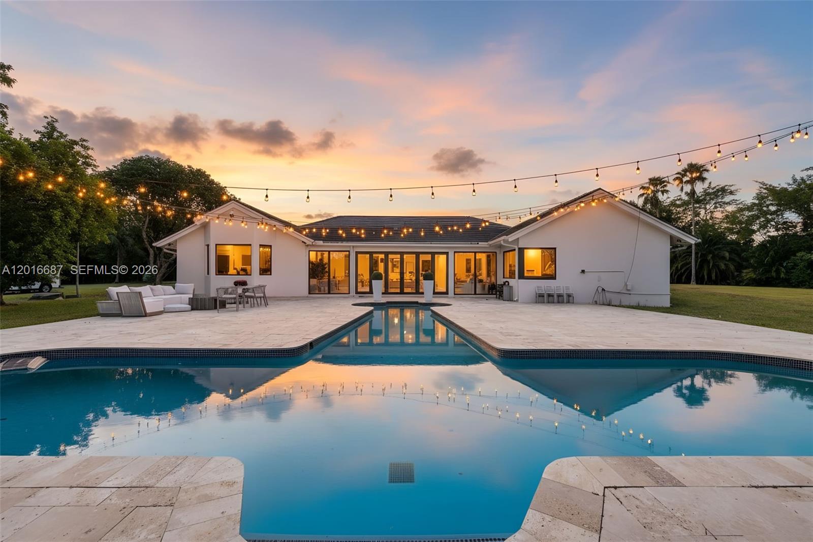 A white house with a large pool and string lights at sunset — 17795 SW 158th St, Miami FL 33187, MIAMI, FL