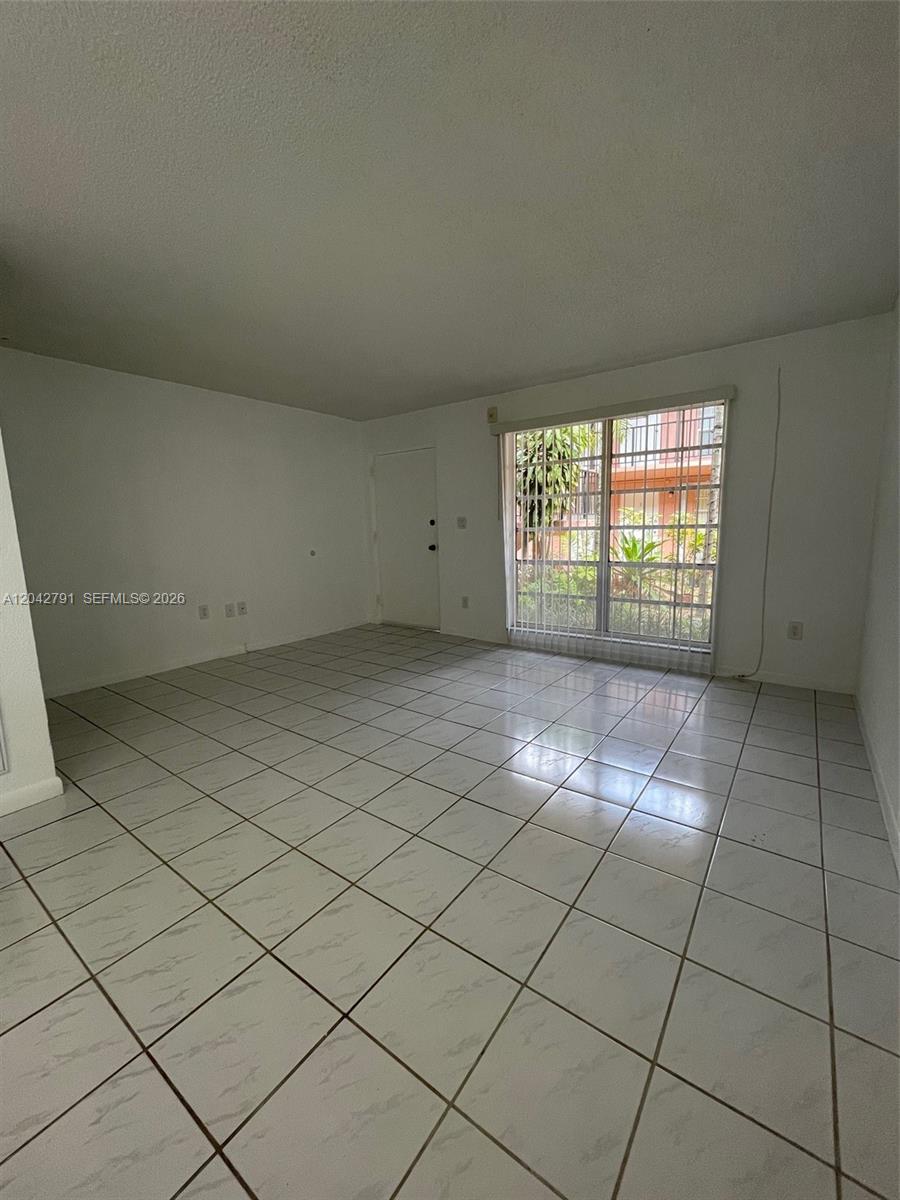 An empty room features white walls, light-colored tile flooring, and a large sliding glass door — 10832 SW 88th St # U13, Miami FL 33176, MIAMI, FL