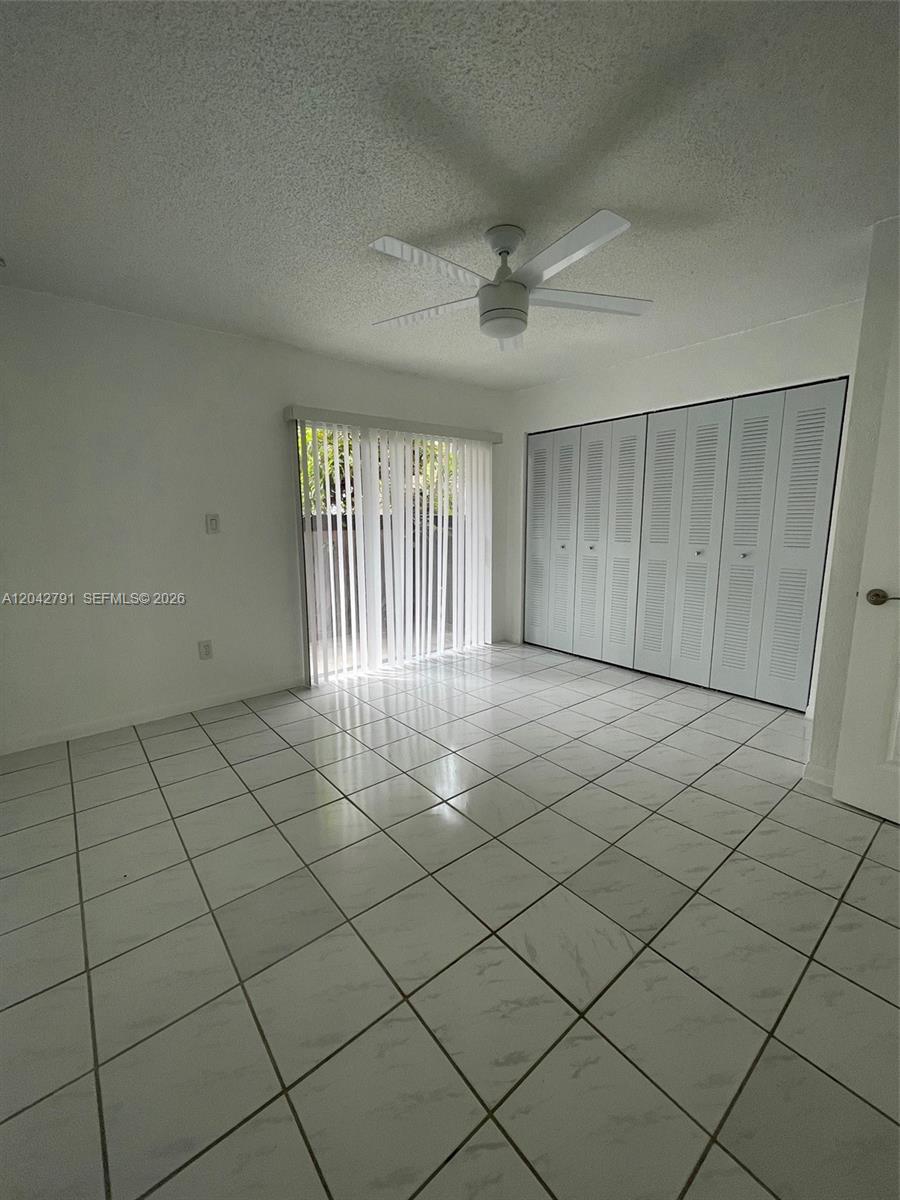 A bedroom features white tile floors, a ceiling fan, and a large louvered closet — 10832 SW 88th St # U13, Miami FL 33176, MIAMI, FL