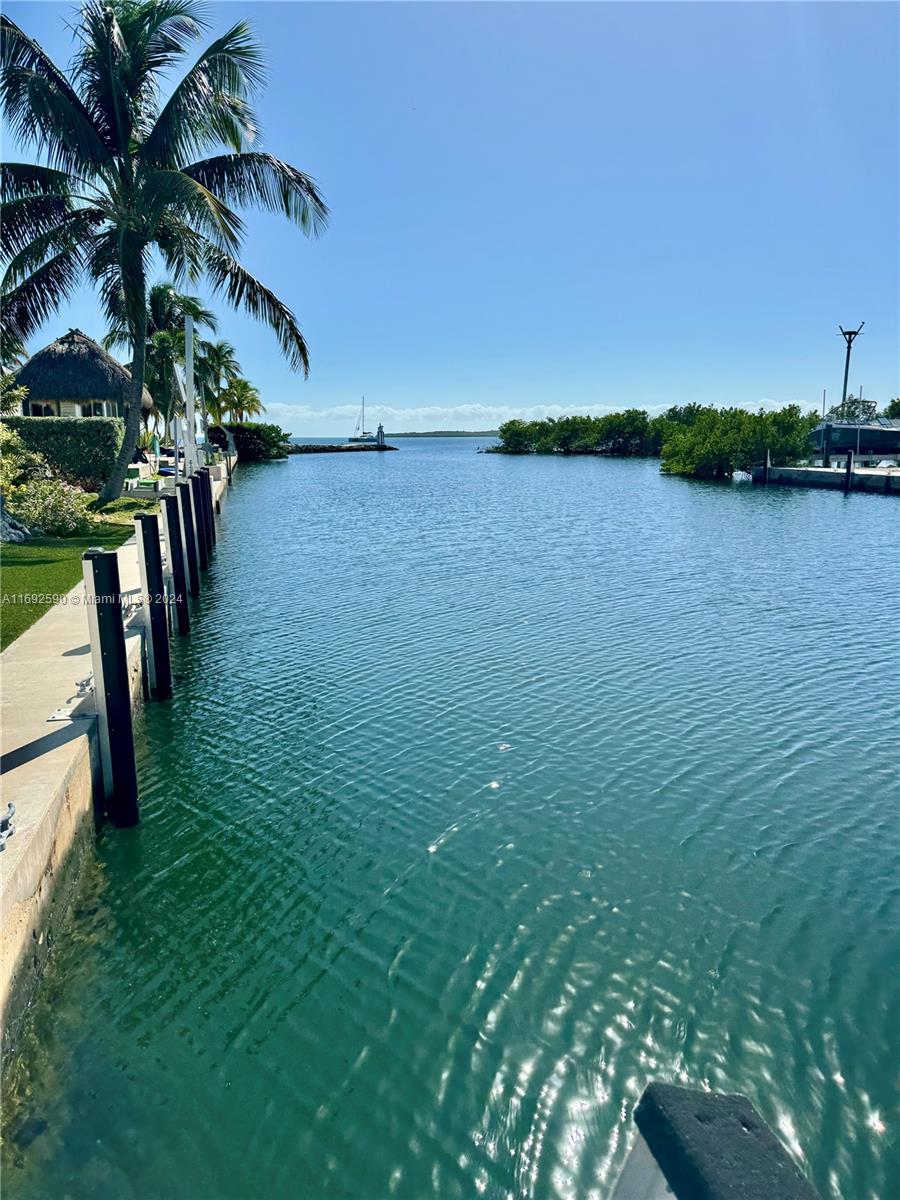 A view of a canal leading to open water with a dock and palm trees — 72 Ocean Dr # 0, Key Largo FL 33037, KEY LARGO, FL