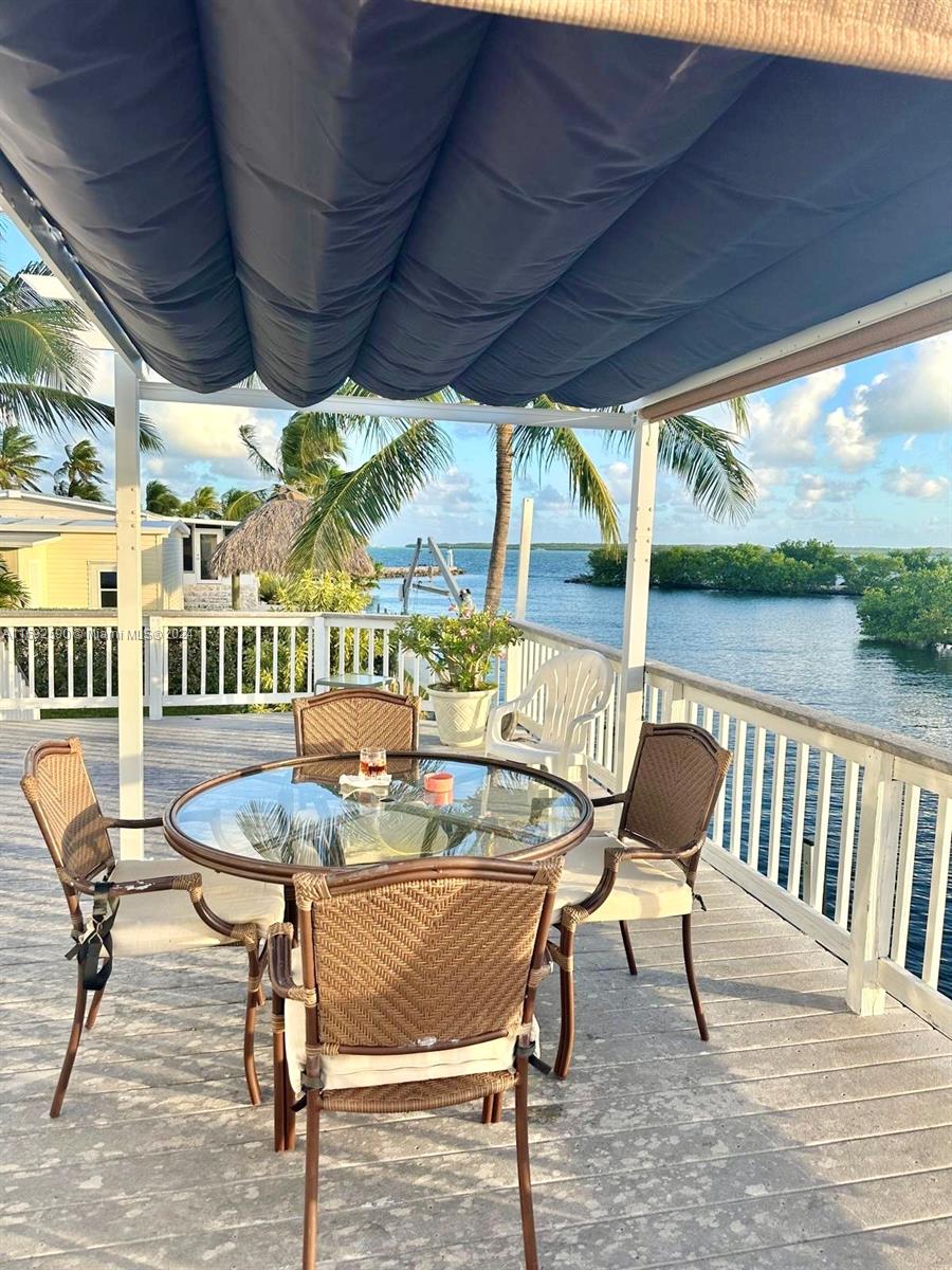 A patio deck features a glass-topped table with chairs under a retractable fabric canopy — 72 Ocean Dr # 0, Key Largo FL 33037, KEY LARGO, FL