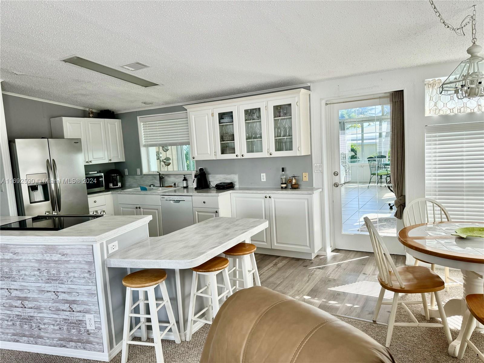 A kitchen features white cabinets, a breakfast bar with stools, and a dining area — 72 Ocean Dr # 0, Key Largo FL 33037, KEY LARGO, FL
