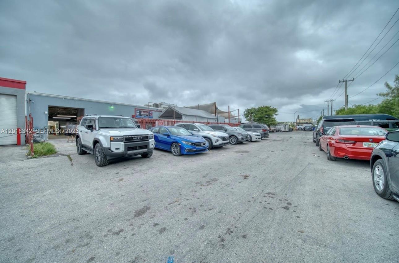 A gravel parking lot features several parked cars in front of a commercial warehouse building — 3730 NW 82nd St, Hialeah FL 33147, HIALEAH, FL