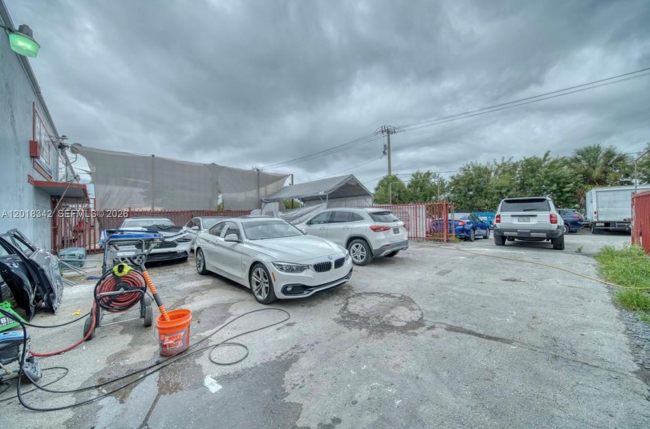 An outdoor parking lot features several cars, a pressure washer, and a metal fence — 3730 NW 82nd St, Hialeah FL 33147, HIALEAH, FL