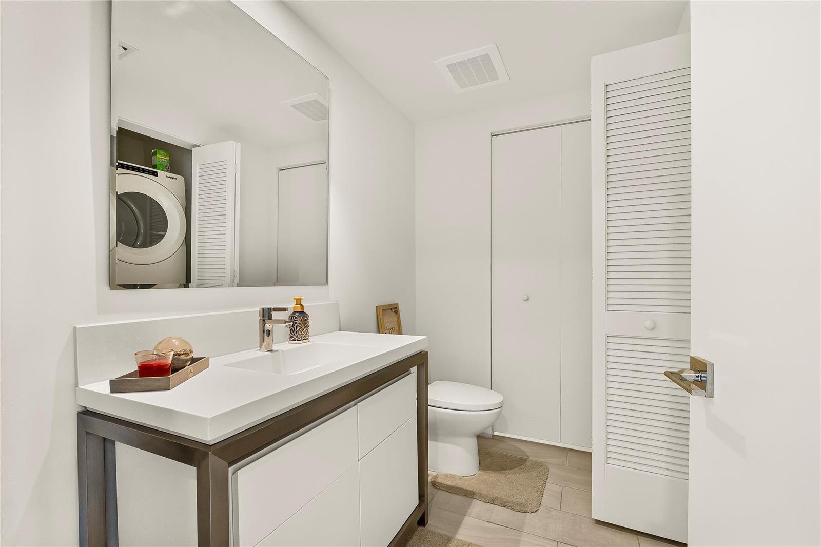 A modern bathroom features a white vanity, a large mirror, and a toilet — 2000 Metropica Way # 216, Sunrise FL 33323, SUNRISE, FL