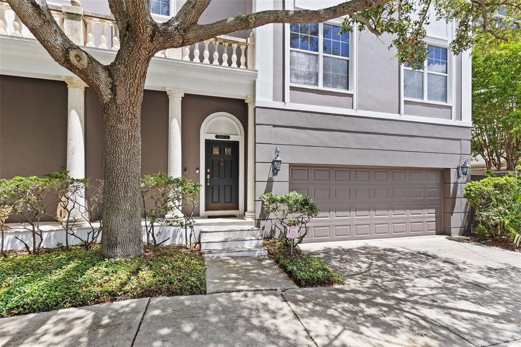 The exterior of a multi-story home features a dark front door, garage, and large tree — 3007 W MASON STREET UNIT A, TAMPA, FL
