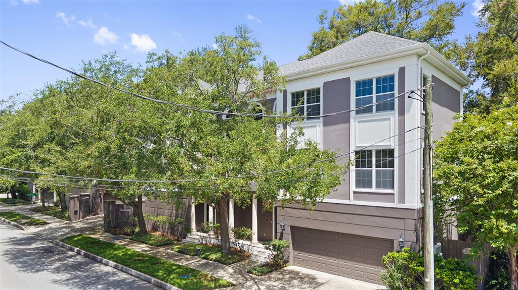 An exterior view of a multi-story house with a garage and surrounding trees — 3007 W MASON STREET UNIT A, TAMPA, FL