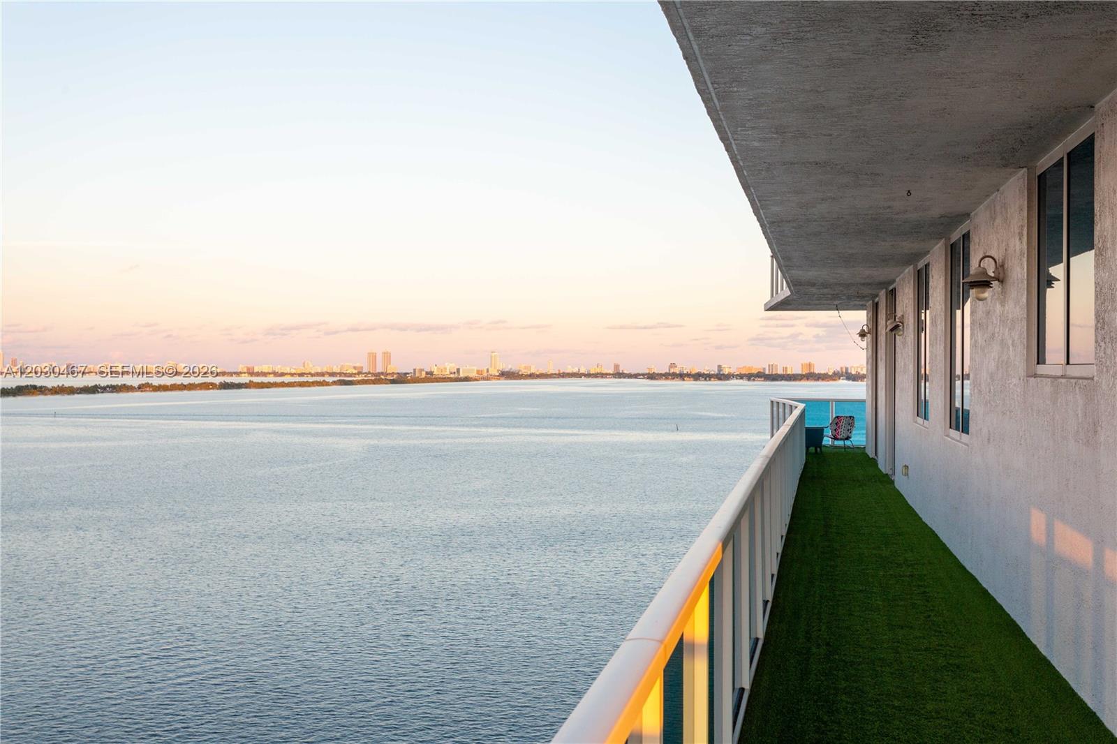 A high-rise balcony features artificial turf flooring, a white railing, and panoramic water views — 700 NE 25th St # 1003, Miami FL 33137, MIAMI, FL