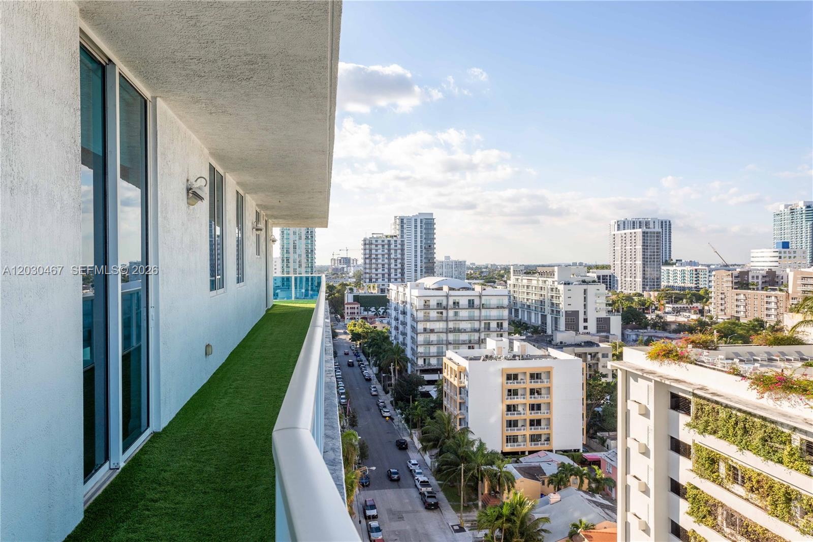 A balcony with artificial turf overlooks a city street lined with mid-rise apartment buildings — 700 NE 25th St # 1003, Miami FL 33137, MIAMI, FL