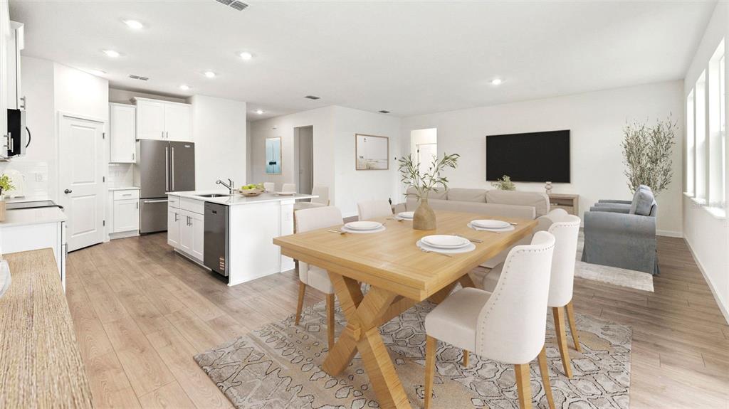 An open-concept kitchen, dining area, and living room feature light wood floors and white cabinetry — 300 BRACER WAY, ORMOND BEACH, FL