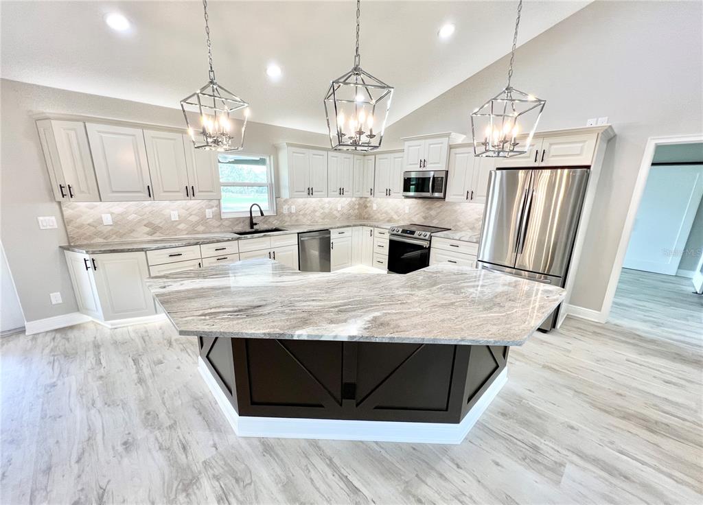 A kitchen features light-colored cabinetry, a dark wood island, and stone countertops — 6425 SW 180TH CIRCLE, DUNNELLON, FL