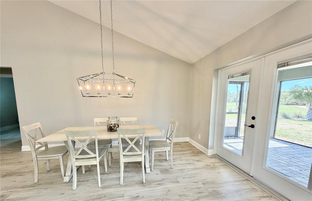 A dining room with a vaulted ceiling, a rectangular chandelier, and light wood-look flooring — 6425 SW 180TH CIRCLE, DUNNELLON, FL