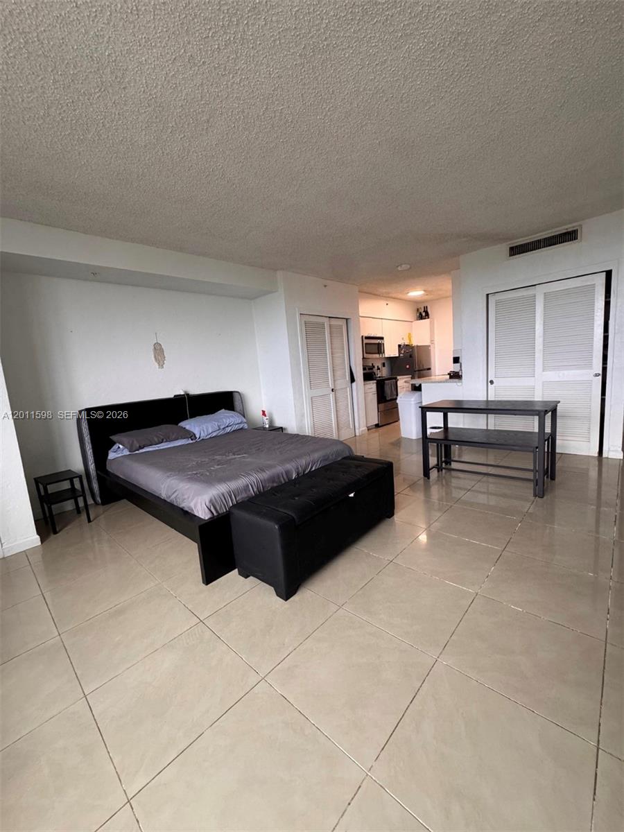 A studio apartment features a bed, a dining table, and a kitchen with tiled floors — 1500 Bay Rd # 1576S, Miami Beach FL 33139, MIAMI BEACH, FL