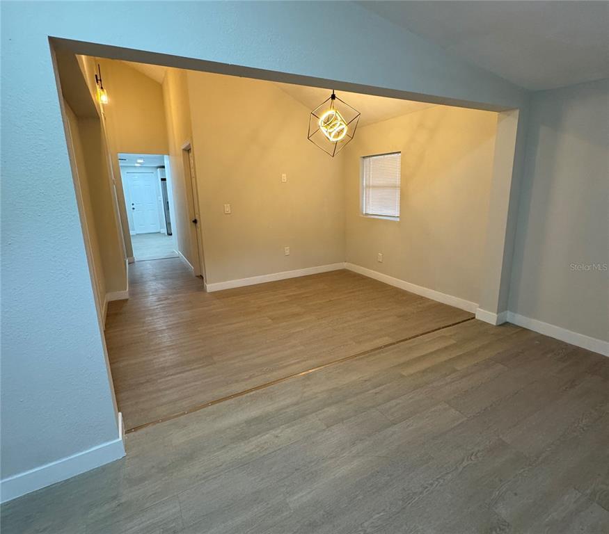 An interior view shows a dining area with wood-look flooring and a geometric pendant light — 8014 N ALASKA STREET, TAMPA, FL