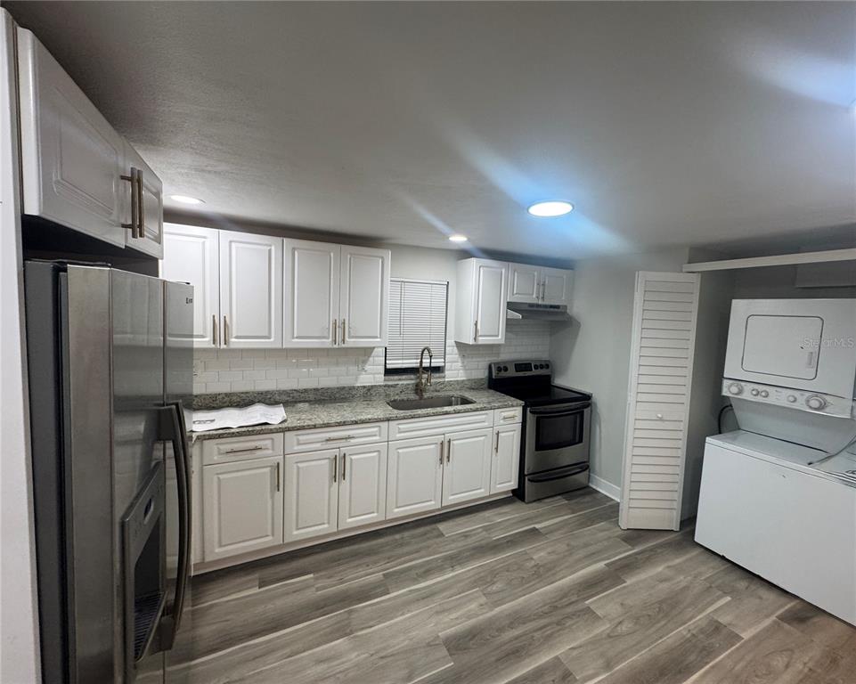 A kitchen with white cabinets, granite countertops, stainless steel appliances, and wood-look flooring — 8014 N ALASKA STREET, TAMPA, FL