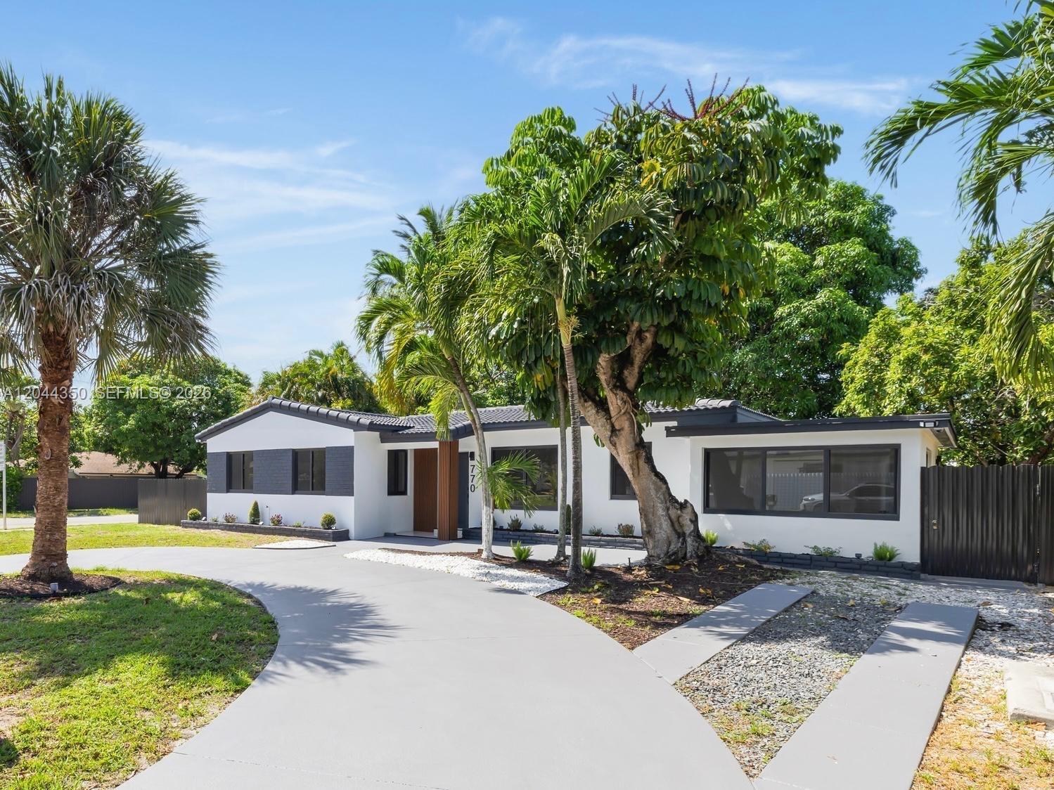A single-story house with a white exterior, dark trim, and a curved concrete driveway — 770 NE 160th St, Miami FL 33162, MIAMI, FL