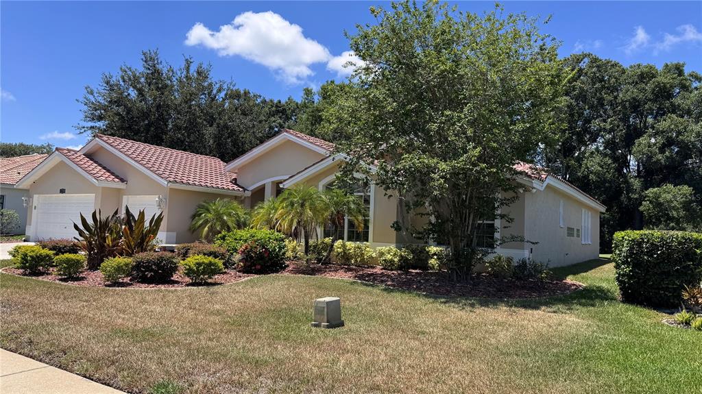 A single-story house with a beige exterior, tile roof, and a two-car garage — 1230 BERKSHIRE LANE, TARPON SPRINGS, FL