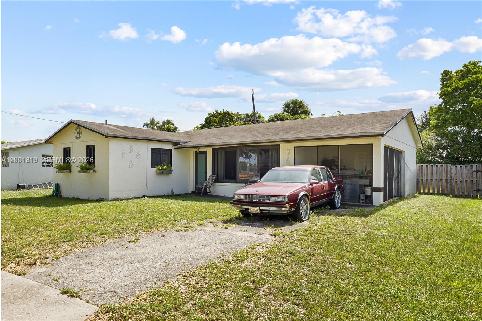 A single-story house with a maroon sedan parked in the carport on a grassy lot — 761 NW 65th Ave, Margate FL 33063, MARGATE, FL