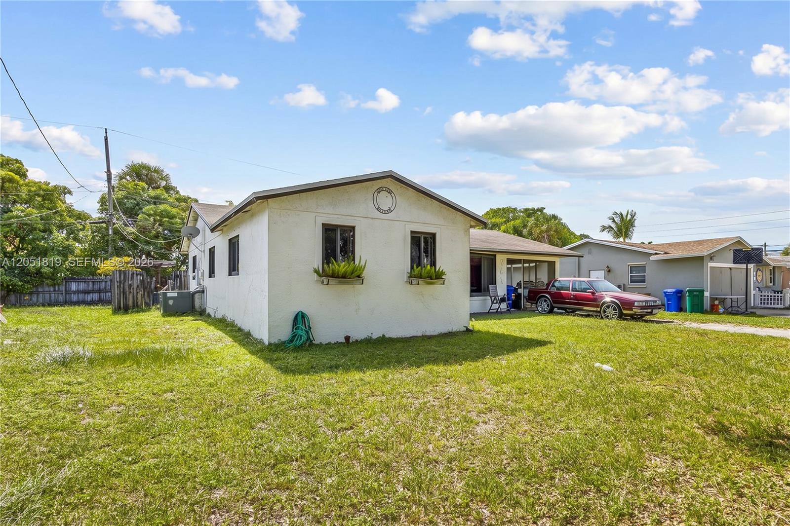 A white single-story house with a grassy yard and a parked car in the driveway — 761 NW 65th Ave, Margate FL 33063, MARGATE, FL
