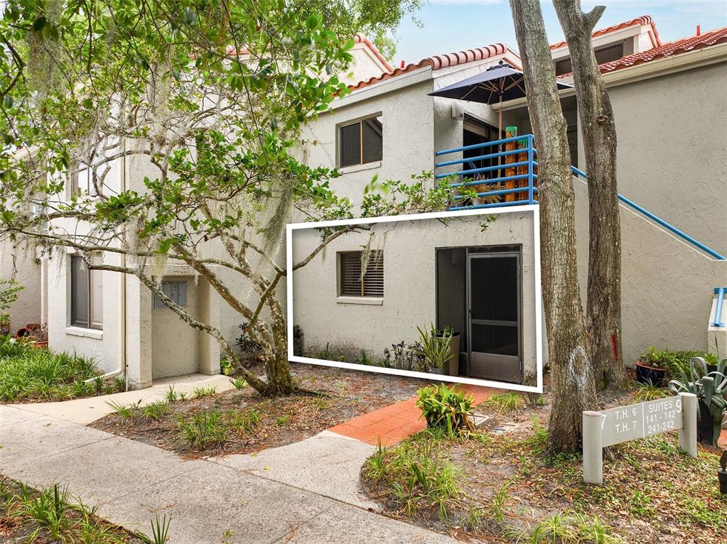 A ground-level apartment entrance with a screen door and window, viewed from a sidewalk — 1000 WINDERLEY PLACE UNIT 141, MAITLAND, FL