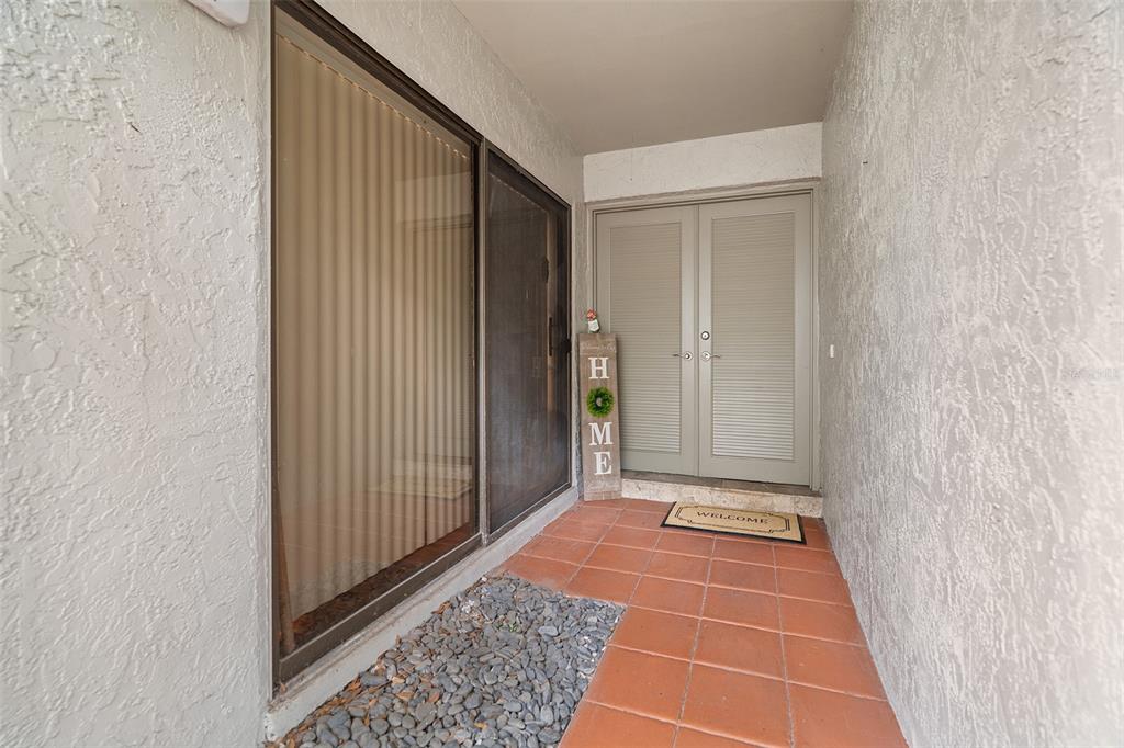 An entryway features a tiled floor, a sliding glass door, and double louvered doors — 1000 WINDERLEY PLACE UNIT 141, MAITLAND, FL