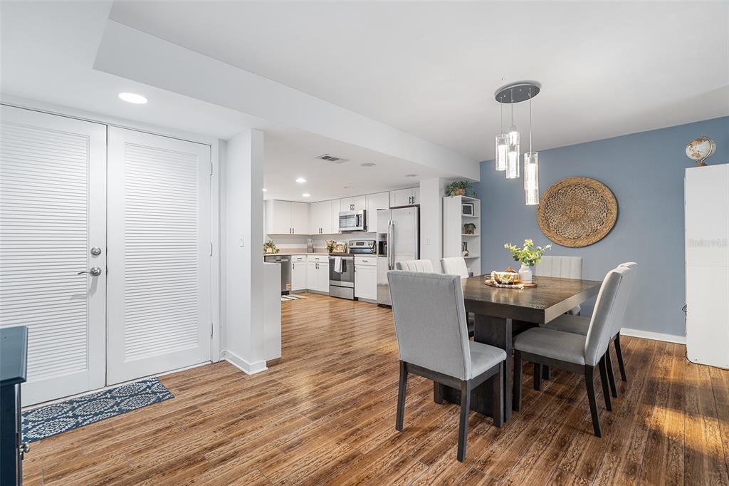 A dining area with a wooden table and chairs opens into a white kitchen — 1000 WINDERLEY PLACE UNIT 141, MAITLAND, FL