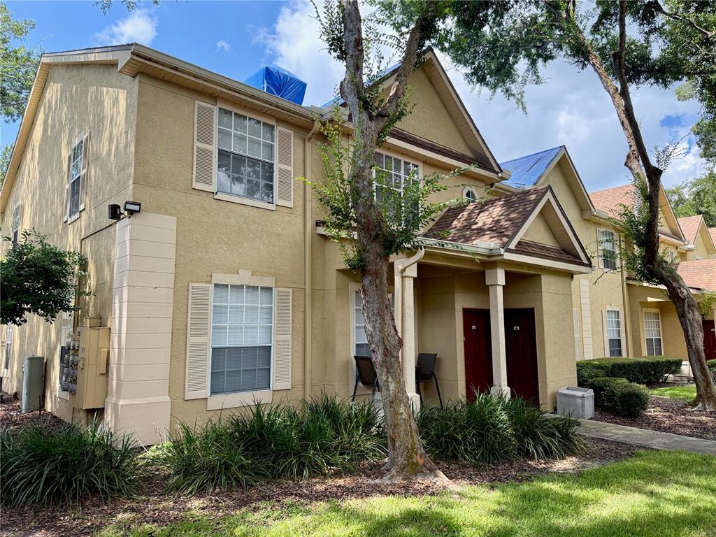 A two-story tan stucco apartment building with blue tarps on the roof — 826 GRAND REGENCY POINT UNIT 203, ALTAMONTE SPRINGS, FL