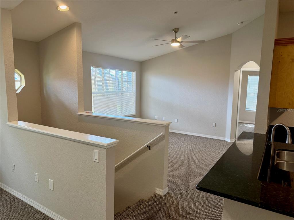 A carpeted living area overlooks a staircase with a half-wall and a ceiling fan — 826 GRAND REGENCY POINT UNIT 203, ALTAMONTE SPRINGS, FL
